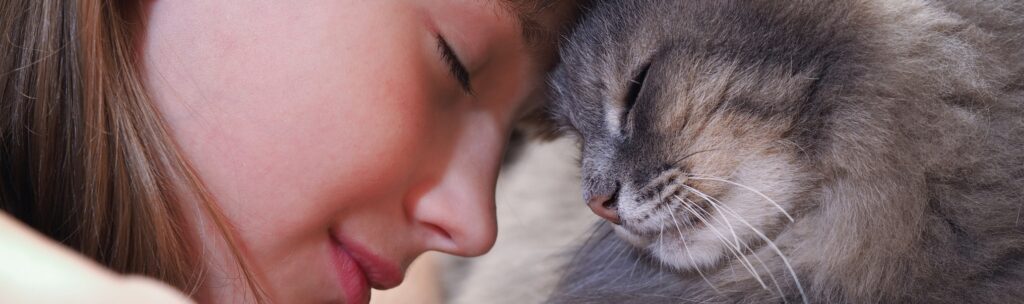 a child and a cat touching foreheads